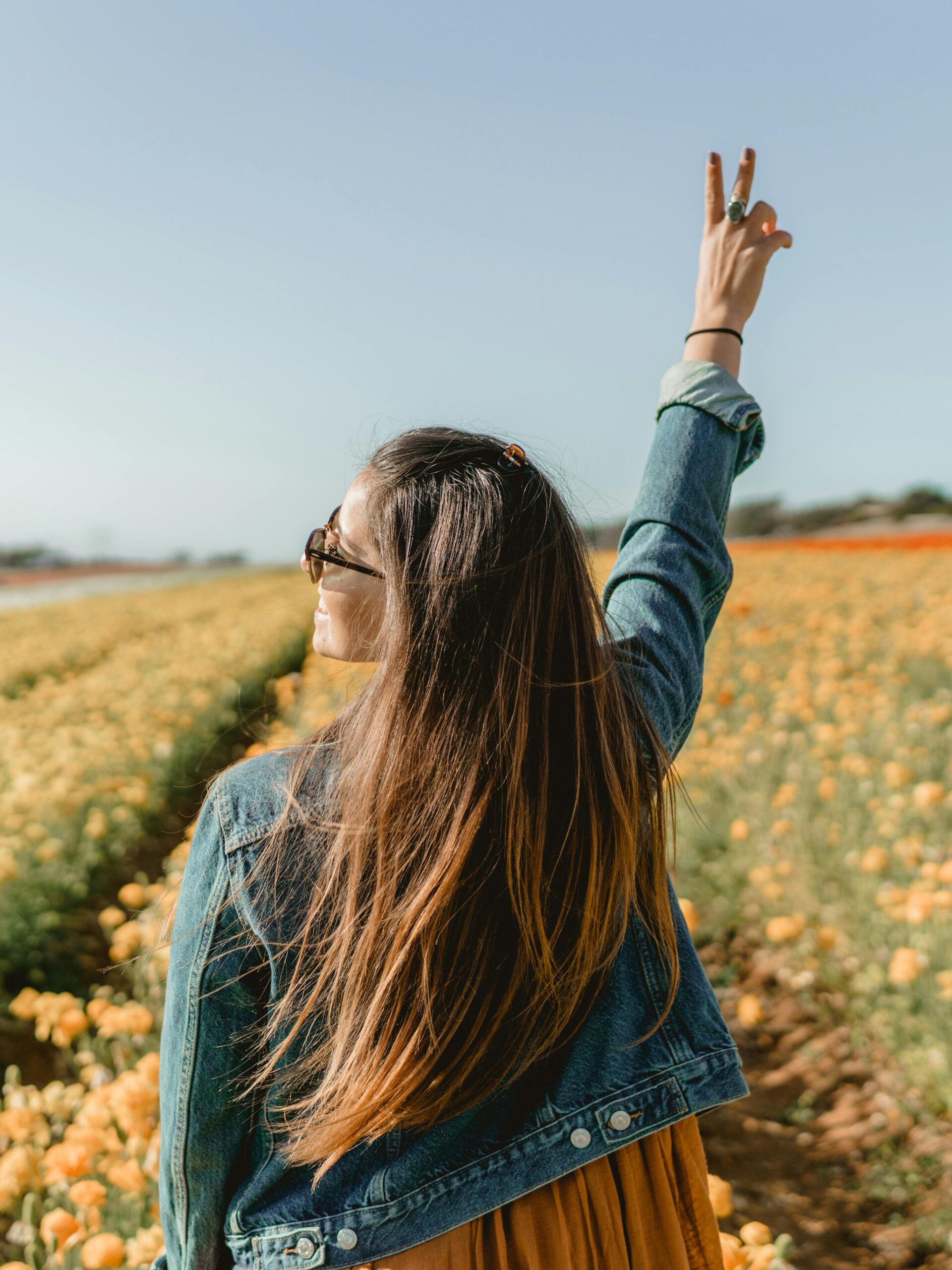 A woman enjoying a sunny day in a vivid yellow flower field in Carlsbad, CA.